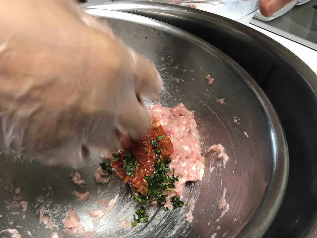 よく練ったひき肉にお好みの材料を加えてよく混ぜていきます。一つ目のフレーバーは、先生のお手製のセミドライトマトとバジルを加えた「イタリアンバージョン」。